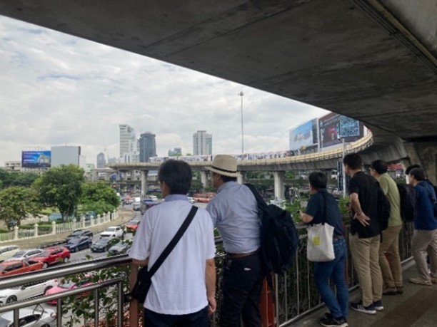 Some people standing and observing the traffic from a bridge